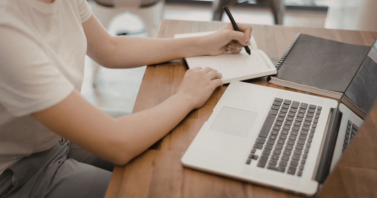 Estudiante investigando los cambios en las visas de estudiante en Canadá frente a su laptop y libreta.