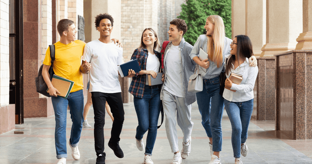 Grupo de jóvenes estudiantes internacionales caminando alegres por el campus de una institución en Canadá.