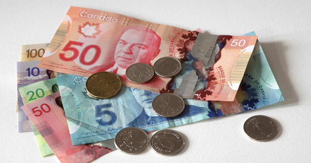 Billetes y monedas de dólares canadienses (CAD) sobre un fondo blanco